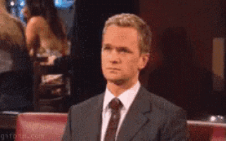 a man in a suit and tie is sitting in a chair looking at something