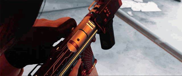 a close up of a person holding a gun with a red stripe on the barrel