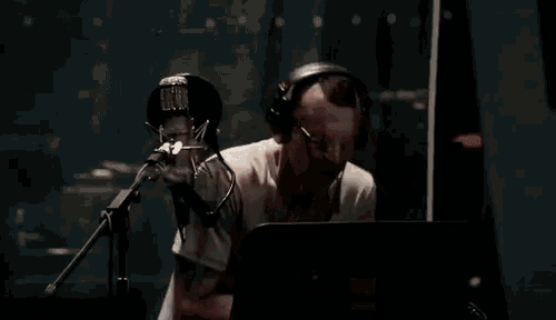 a man wearing headphones is singing into a microphone in a recording studio .