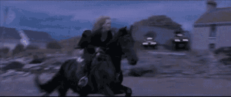 a woman is riding on the back of a black horse .