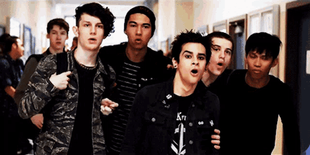 a group of young men are walking down a hallway and one of them is wearing a shirt that says krt on it