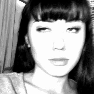 a black and white photo of a woman 's face with long hair .