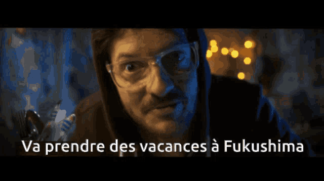 a man wearing glasses and a hoodie says va prendre des vacances à fukushima
