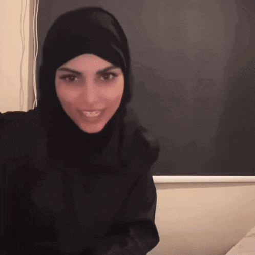 a woman wearing a black hijab looks at the camera