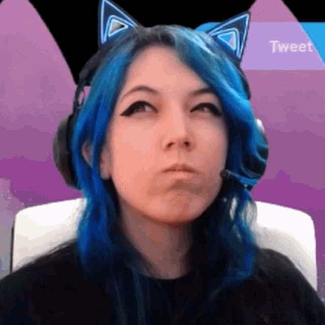 a woman with blue hair and cat ears is wearing headphones and a microphone .