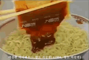 a close up of a bowl of noodles with chopsticks and sauce coming out of it