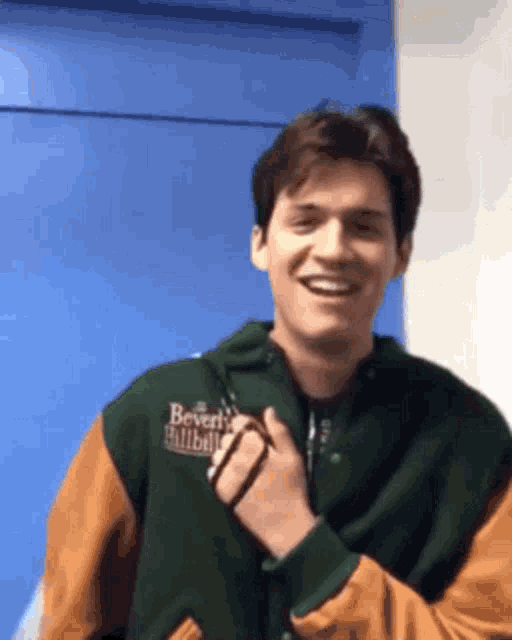 a young man wearing a green and brown jacket with the word beverly on it