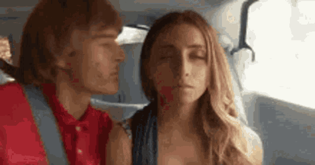a man and a woman are kissing in a car .