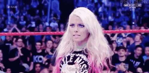 a woman is standing in a wrestling ring with a crowd behind her .