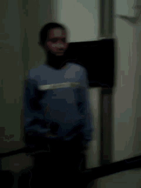 a blurry picture of a person standing in front of a refrigerator .