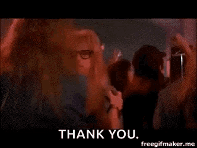 a man in a wig and glasses is dancing in a crowd with the words `` thank you '' .