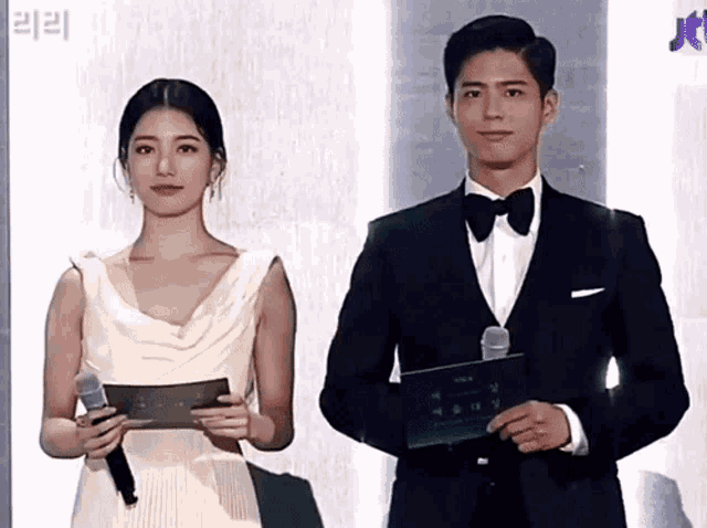 a man in a tuxedo and a woman in a white dress stand next to each other