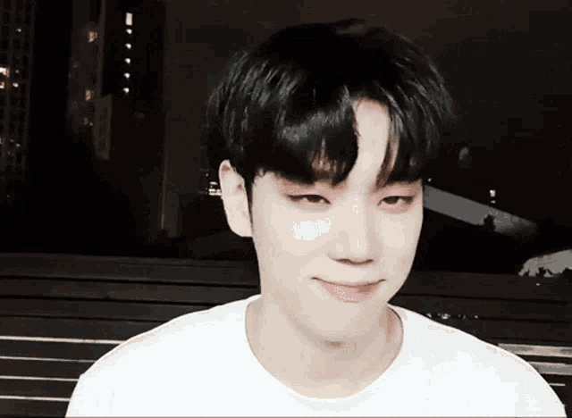 a young man with black hair and a white shirt smiles