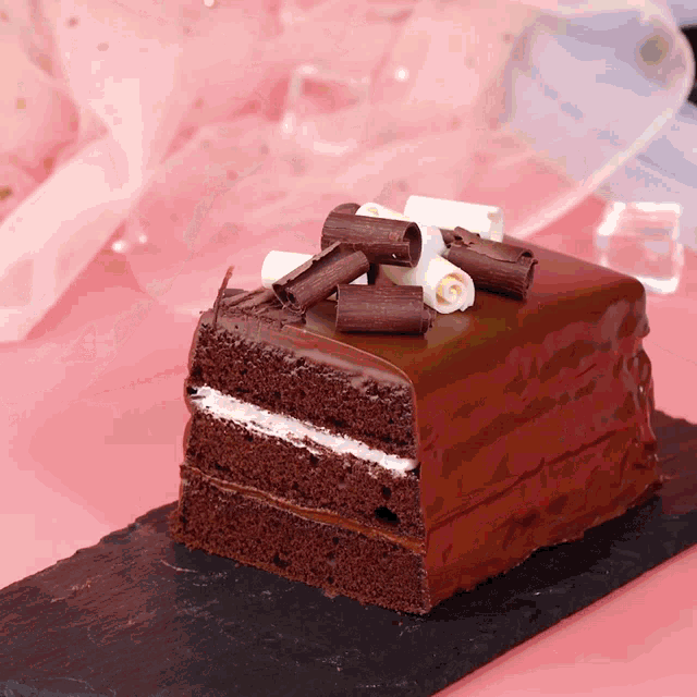 a slice of chocolate cake with white frosting and chocolate curls on top