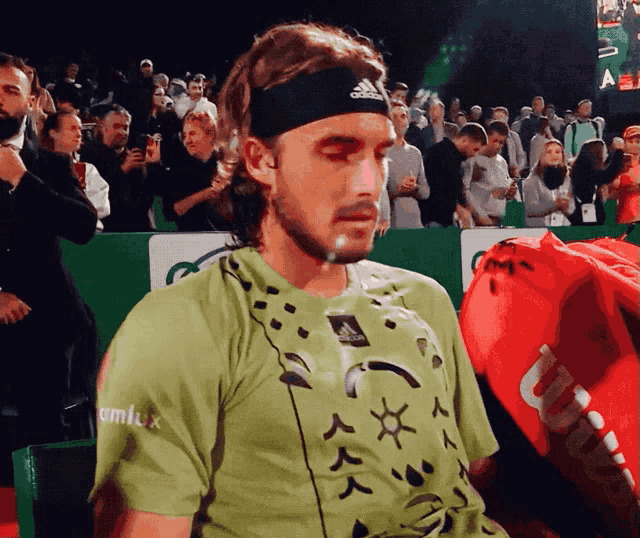 a man wearing an adidas headband looks down