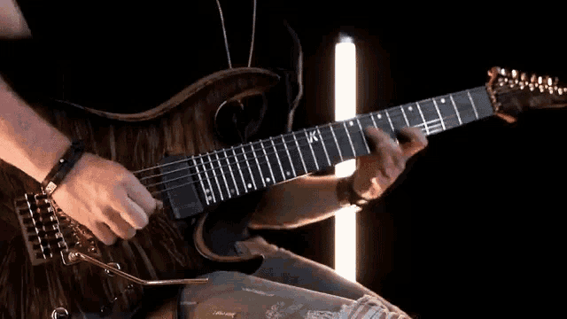 a man is playing a guitar with the letters kc on the neck