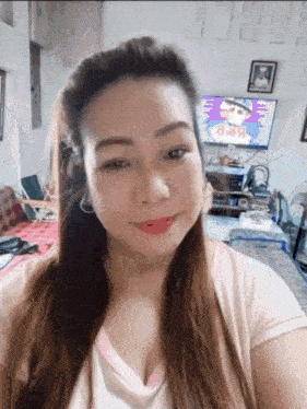 a woman in a pink shirt is smiling in front of a television with a picture of a man on it ..