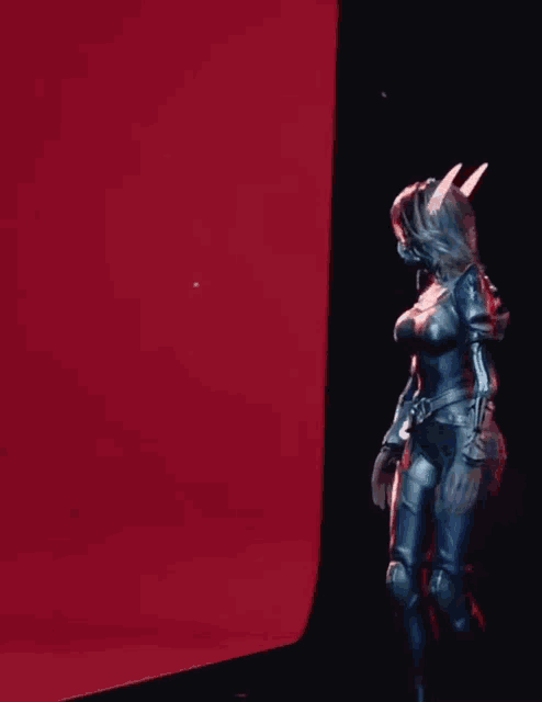 a woman in a superhero costume is standing in front of a red screen .