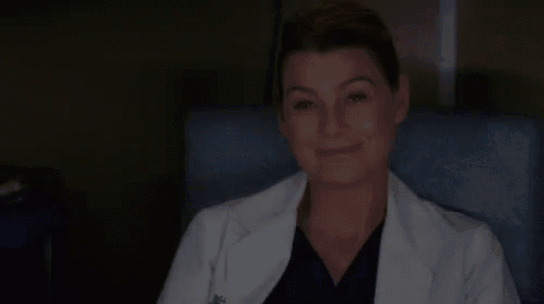a woman in a lab coat is smiling while sitting in a chair .