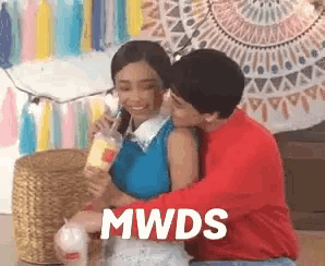 a man is kissing a woman on the cheek while holding a drink in a cup .