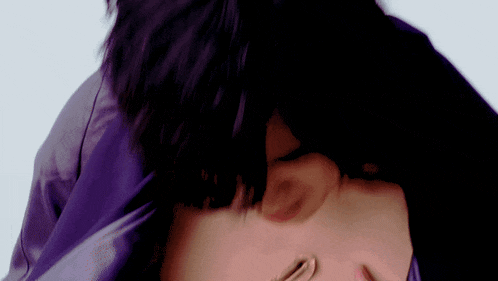 a close up of a person 's face with a purple jacket on
