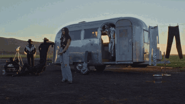 a woman stands in front of a silver airstream