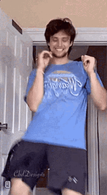 a man in a blue shirt and shorts is dancing in a doorway .