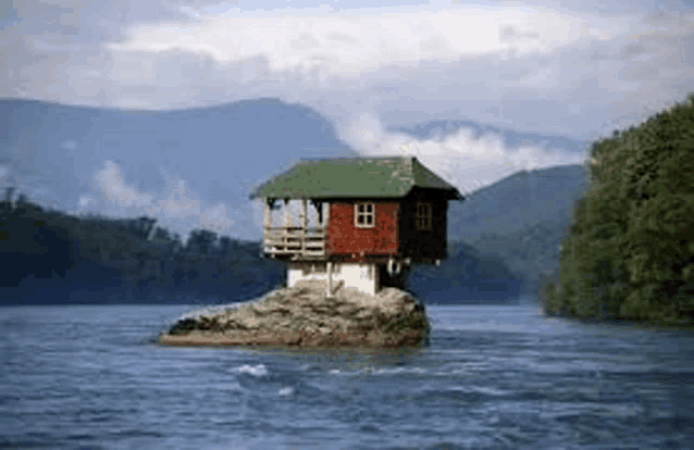 a small house is sitting on top of a rock in the middle of a river .