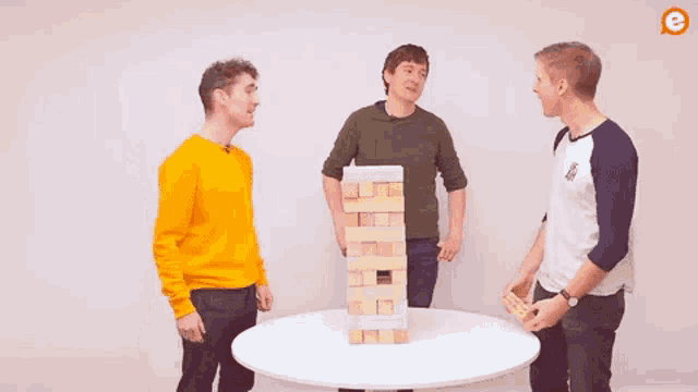 a group of men are playing jenga on a table .