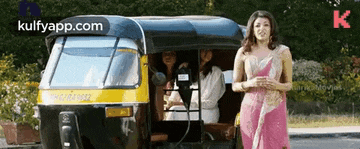 a woman in a pink dress is standing in front of a rickshaw