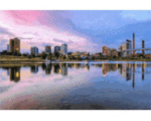 a city skyline is reflected in a lake with a bridge in the background .