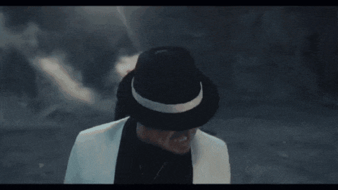 a man wearing a black hat and a white jacket is making a funny face