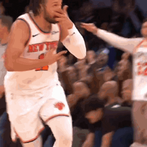 a basketball player wearing a new york jersey is covering his mouth with his hand