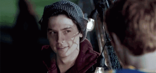 a young man wearing a beanie and a red hoodie is looking at a woman .