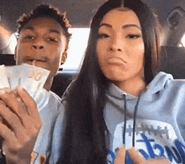 a man and a woman are sitting in the back seat of a car holding money .