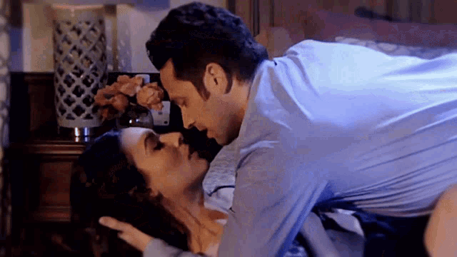 a man in a blue shirt is kissing a woman on the floor