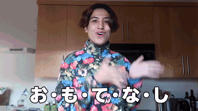a man in a colorful floral jacket is standing in a kitchen with chinese writing on the wall