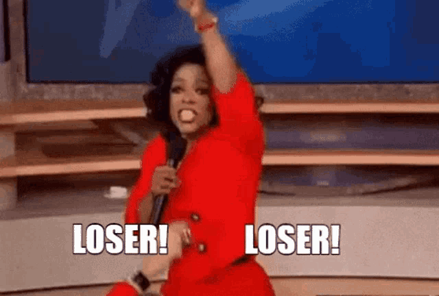 a woman in a red dress is holding a microphone and saying `` loser ! loser ! ''