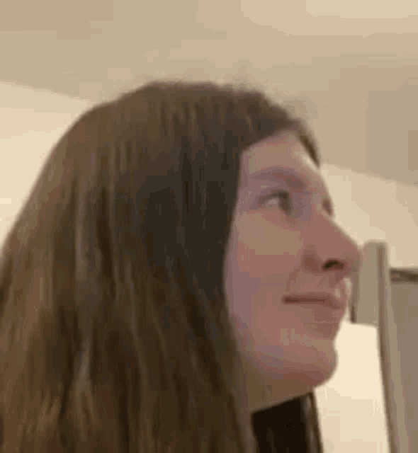 a close up of a woman 's face with long hair looking up at the ceiling .