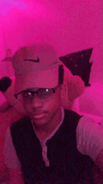a young man wearing a nike hat and glasses takes a selfie