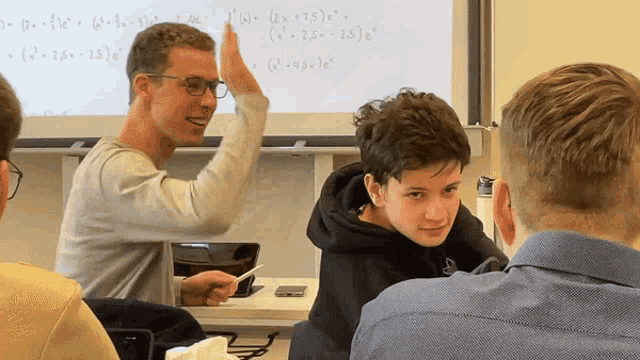 a man giving a high five to another man in front of a white board with math equations