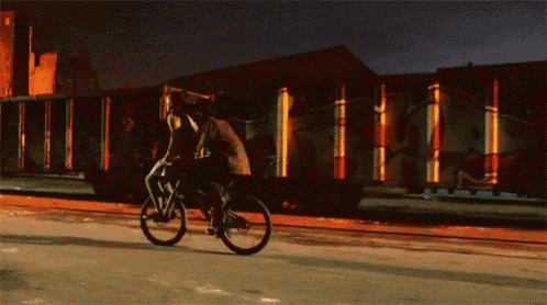 a person riding a bike in front of a building with graffiti on it at night