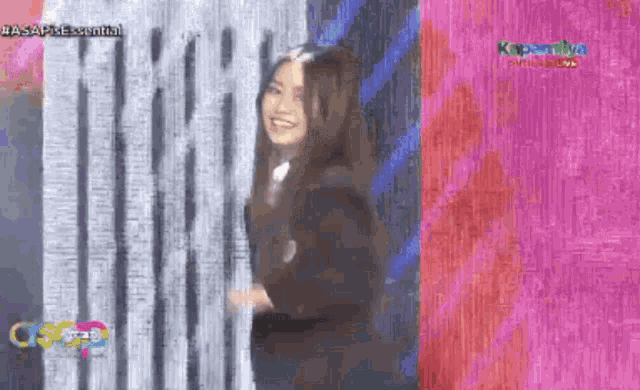 a woman in a black suit is standing in front of a curtain .