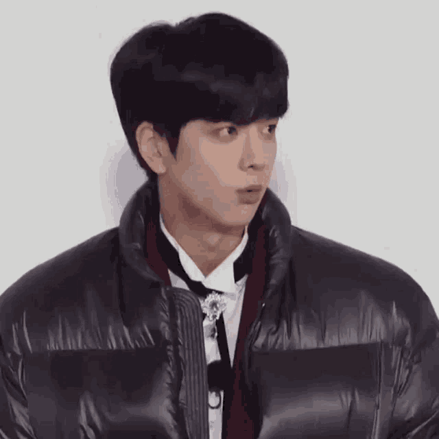 a young man is wearing a black jacket and a red scarf