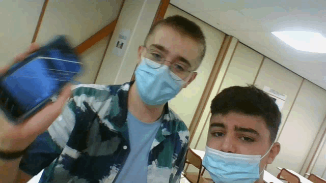 two men wearing face masks pose for a picture