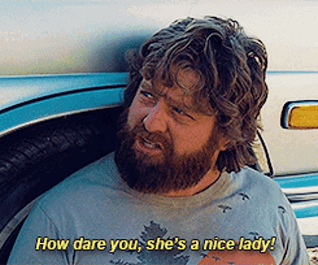 a man with a beard and a shirt that says how dare you she 's a nice lady on it