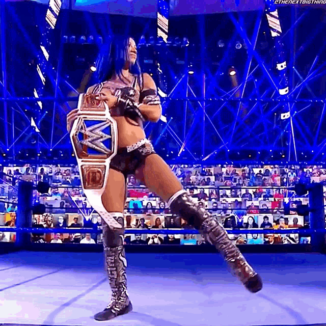 a female wrestler is holding a world heavyweight championship belt in front of a crowd