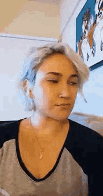 a woman with a nose ring is sitting in front of a painting .