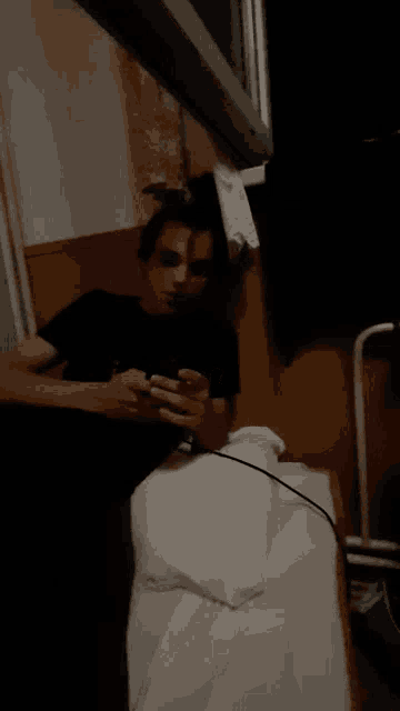a man laying on a bed looking at his cell phone