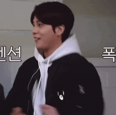 a man wearing a black jacket and a white hoodie is smiling and dancing .